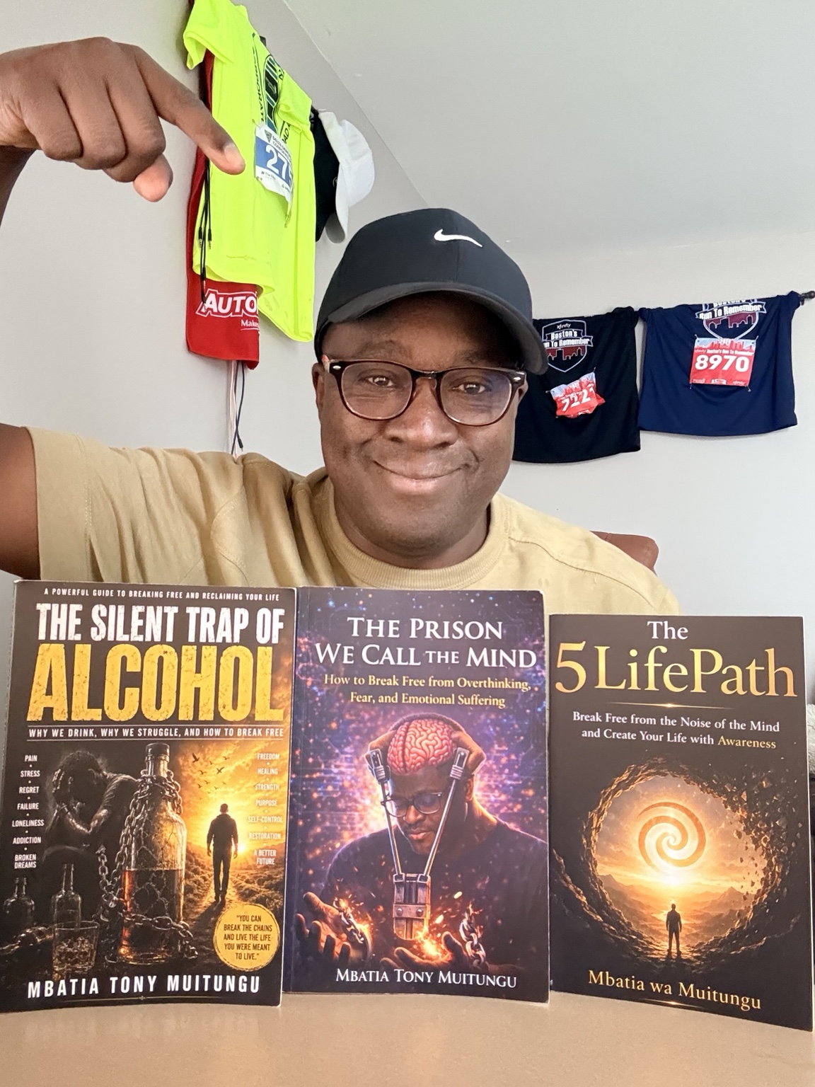 Author Mbatia Muitungu holding his three published books